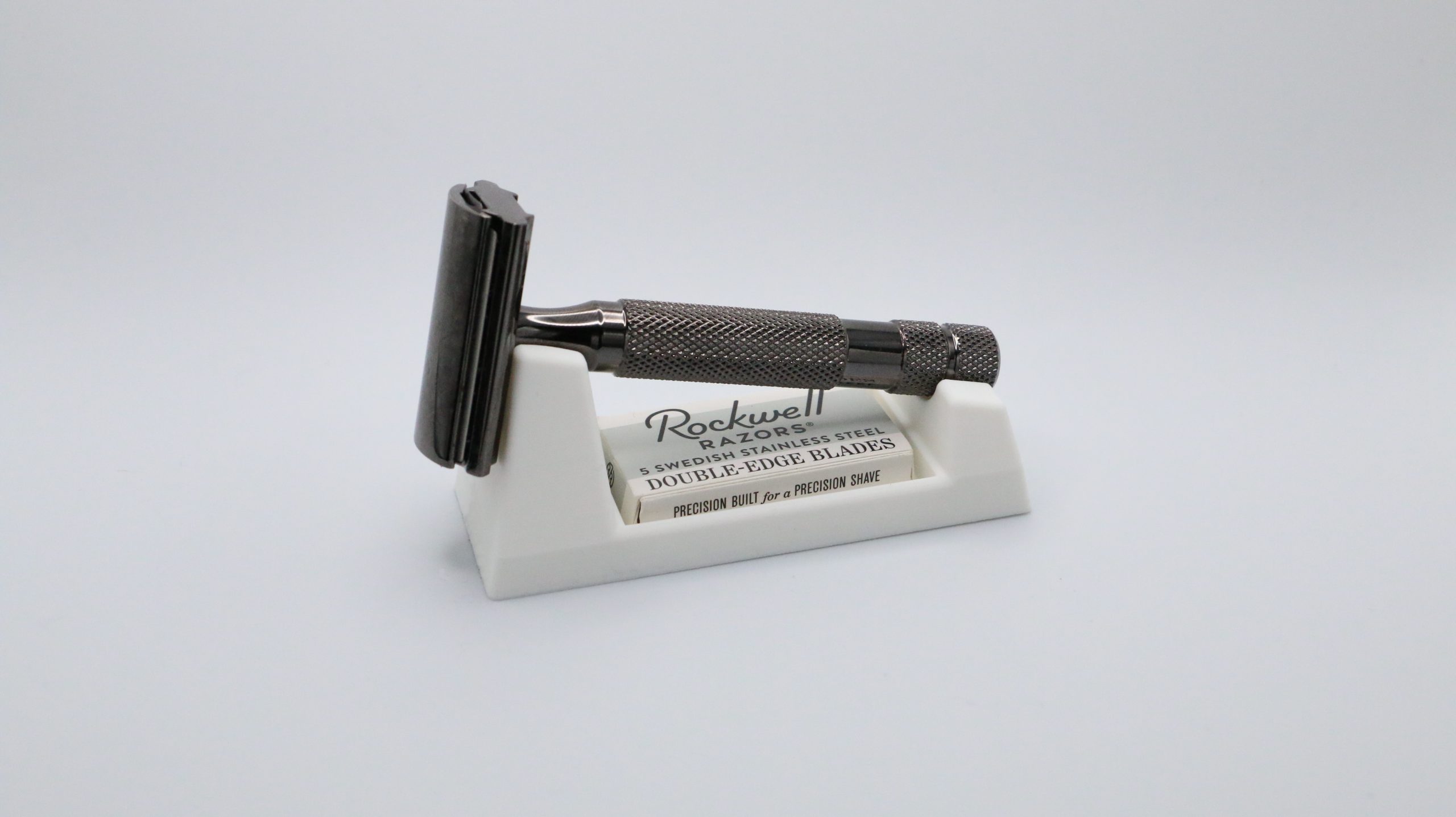Three quarter view of the ivory wedge with the razor resting head up on the high end, blade box in the slot, soft studio shadow under the base.