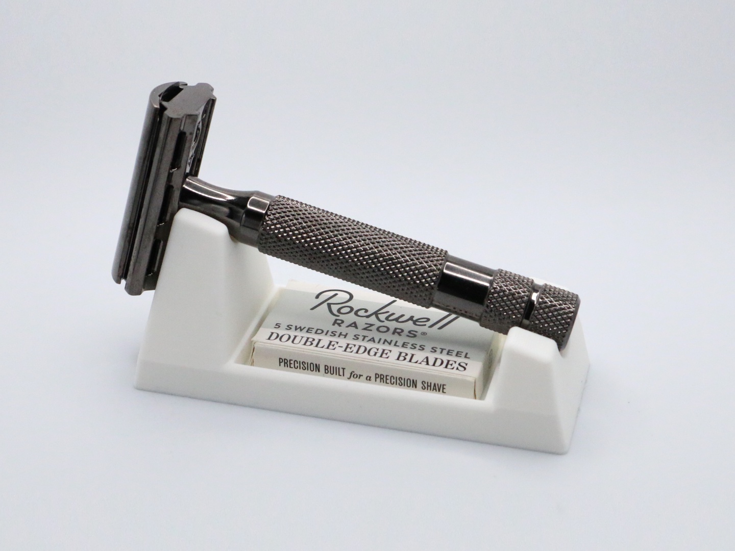 Three quarter close view of the ivory wedge with the razor lying along it, the Rockwell blade box in the slot reading 5 SWEDISH STAINLESS STEEL DOUBLE-EDGE BLADES.