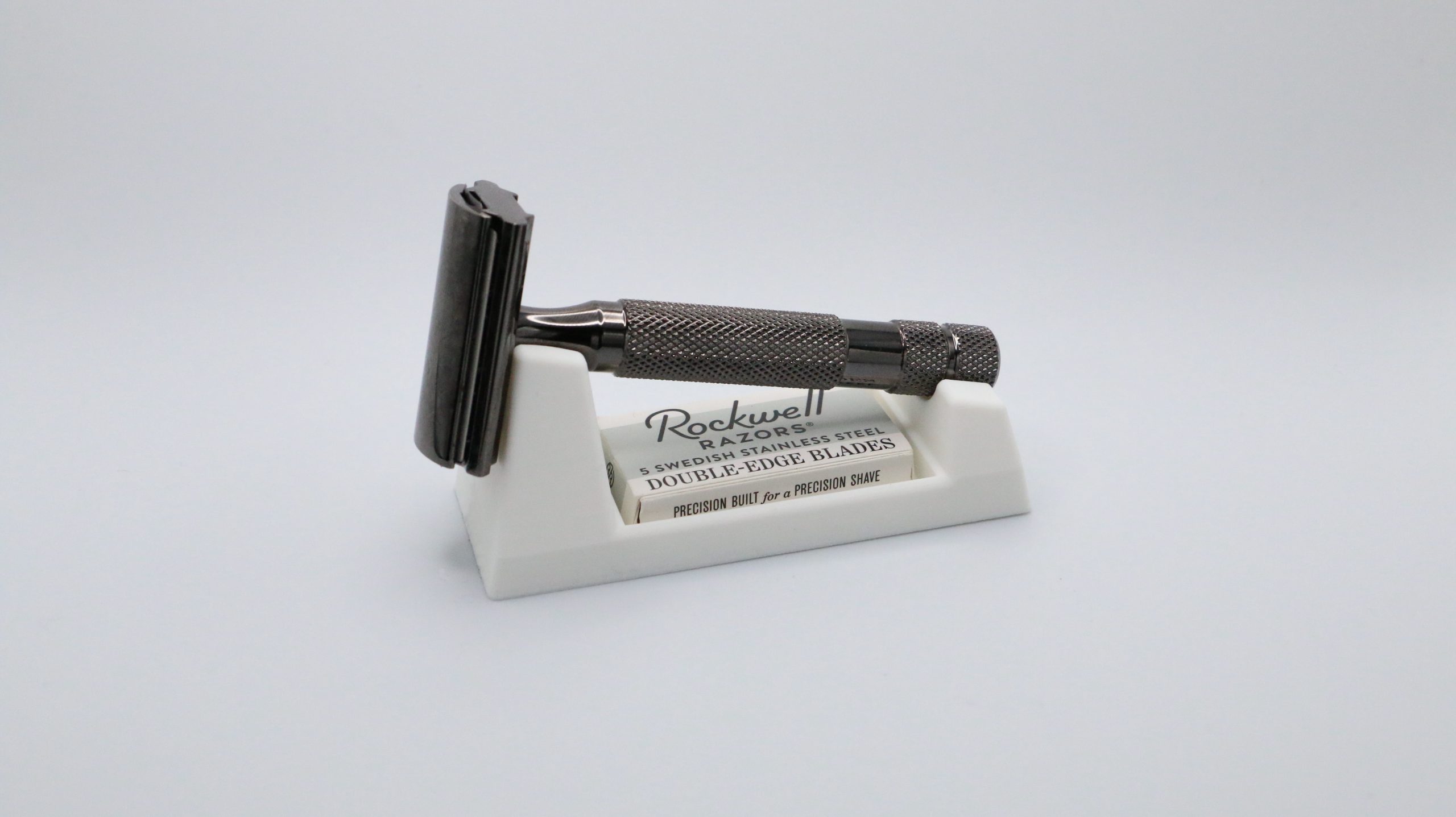 Ivory razor rest seen almost straight on, the razor head raised at the left, handle across the saddle and the blade box just visible in the front slot.