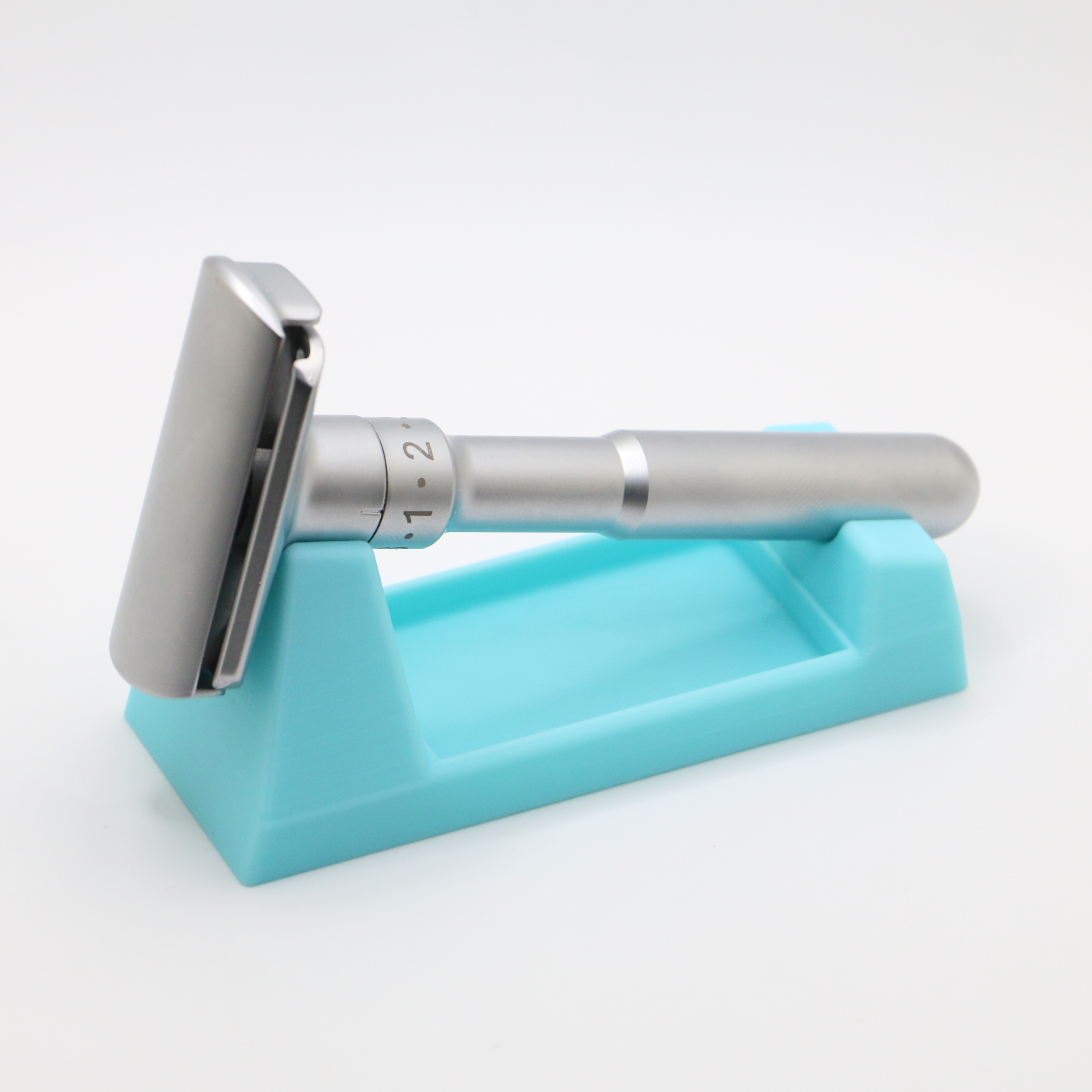 The turquoise stand from a front angle with the razor tipped head down against the saddle, the matte finish and fine print layers catching the light.
