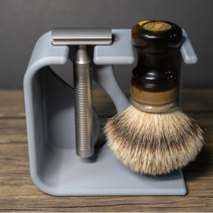 A dove grey 3D printed stand on a wood table holds a steel safety razor and a badger brush with an amber resin handle hanging head down, dark grey backdrop behind.