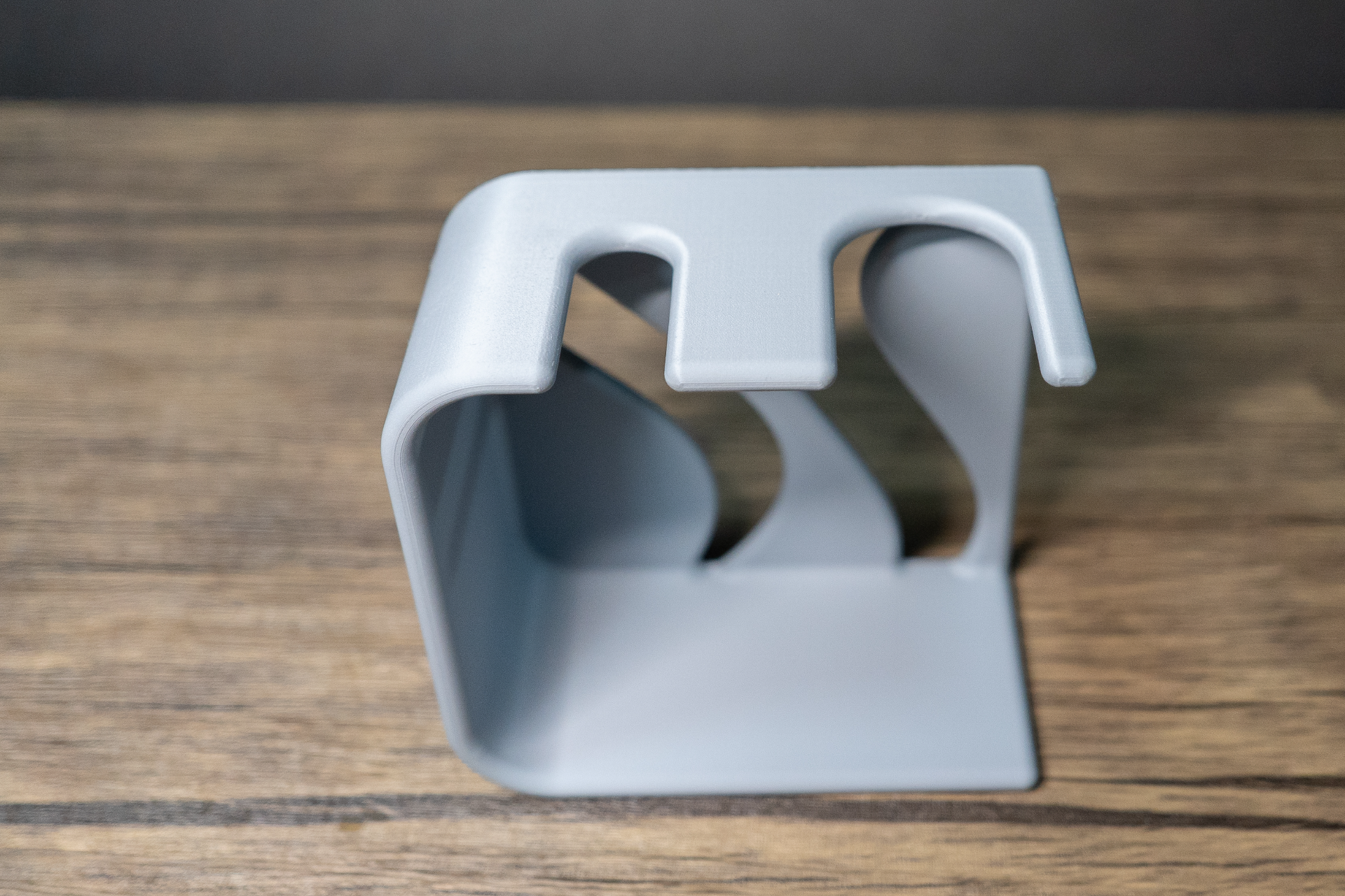 The same grey stand empty, shot from above and slightly behind on weathered wood, showing the two notches in the top rail and the curved inner fins.